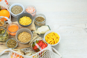 Various vegetarian organic products in glass jars on a white wooden background. Zero waste shopping and sustanable lifestyle concept. Top view, copy space.