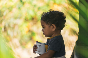 Fototapeta premium latin boy drinking coffee in a white cup, in a natural environment