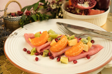 Pancakes. Pink sweet dough with fruits and honey. Tangerines, kiwi, pomegranate seeds. Floral background. Delicious breakfast at home or in a cafe. Selective focus. Shrovetide menu. carnival baking