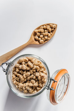 Vista superior de una cuchara de madera y un tarro de cristal lleno de habas de soja texturizada gruesa. Concepto de alternativas veganas a la carne. Prote&iacute;na vegetal. Cocina vegetariana. 