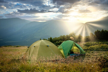 view of tourist tent in mountains at sunrise or sunset. Camping background. Adventure travel active lifestyle freedom concept. Summer vacation. © volody10