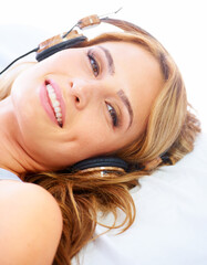 Fototapeta premium Relaxing with some great sounds. Young woman listening to music while wearing a pair of headphones and smiling.