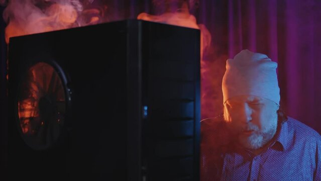 The repair of the gaming computer turned into a short circuit and a fire. White acrid smoke is pouring out of the PC case. The repair specialist is very surprised and annoyed. Funny video.