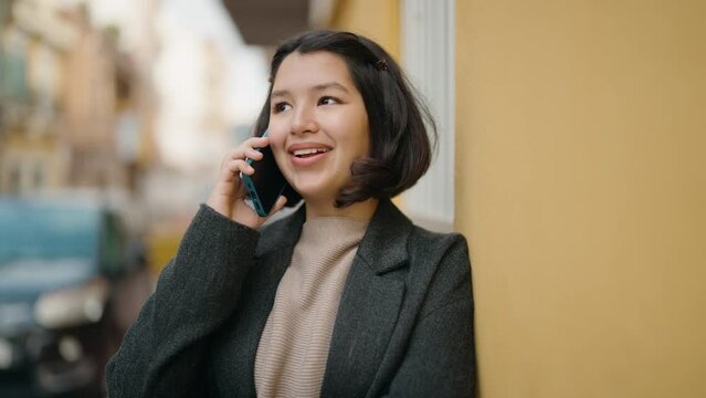 Young hispanic girl smiling confident talking on the smartphone at street