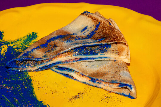 pancake stuffed in blue and glitter gold beautifully arranged on a yellow plate
 art dessert of color creatively