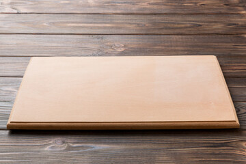 Perspective view of wooden cutting board on wooden background. Empty space for your design
