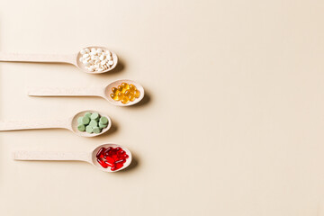 Top view Variety of vitamin and mineral pills in wooden spoon on Colored background. Top view of...