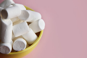 Fototapeta na wymiar white marshmallow in a yellow plate on a pink background