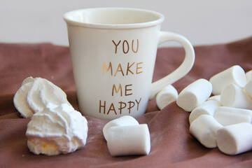 A cup of tea and an airy white marshmallow in a yellow plate on a pink background on a chocolate background