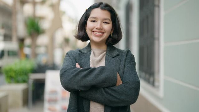 Young hispanic girl smiling confident standing with arms crossed gesture at street
