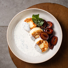 Cottage cheese pancakes, caramel cream sauce with poppy seeds and basil, fresh caramelized plums ( syrniki )