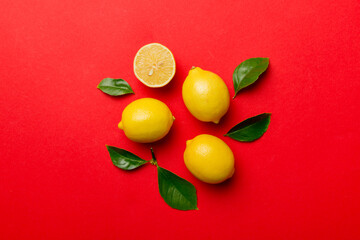 Many fresh ripe lemons with green leaves on colored background, top view, space for text