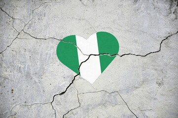 The symbol of the national flag of Nigeria in the form of a heart on a cracked concrete wall.