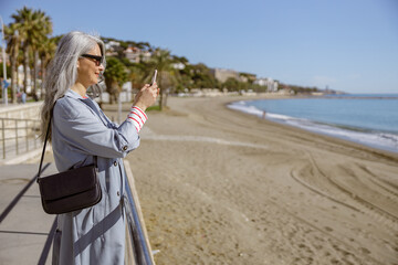 Fototapeta premium Urban lady taking pictures of beautiful coastline