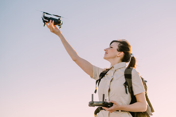 Young woman tourist holds drone in his hand lifting it up.