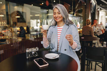 Modern lady sitting with coffee at urban cafe