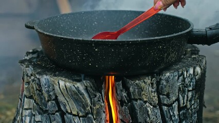 Swedish or finnish log candle. Fire burning from inside the wooden log at day. Cooking on a fire. Cooking in cauldron on Finnish Swedish log stove. Fry sunflower seeds in a pan. - Powered by Adobe