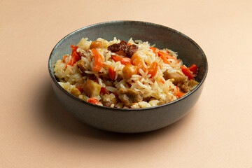 Traditional pilaf with chicken in a plate on a brown background.
