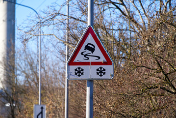 Traffic sign slippery road with icons of snowflake at Zürich Schwamendingen on a sunny winter day. Photo taken February 13th, 2022, Zurich, Switzerland.