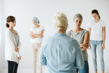 Meeting of group of women talking together during psychotherapy with senior counselor