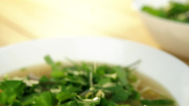 Hand squeezing lemon into asian pho soup