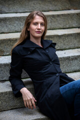 young blonde woman sitting outdoors on stairs