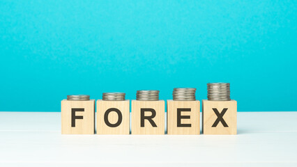 wooden blocks with text forex and coins on wooden table. copy space. blue background