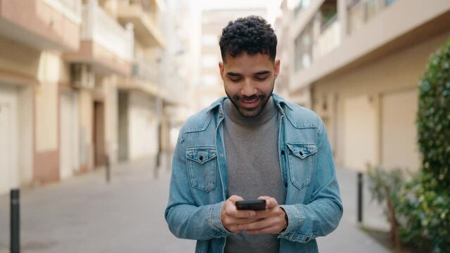 Young arab man using smartphone walking at street
