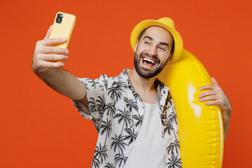 Young smiling tourist man wear beach shirt hat hold inflatable ring doing selfie shot on mobile...