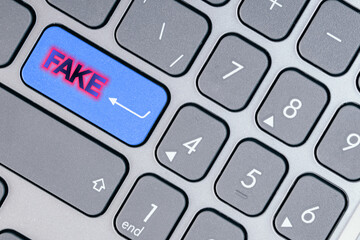 Close-up of a blue button with fake text on a conceptual keyboard. Concept of deception and...