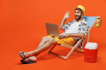 Young tourist man wear beach shirt hat lie on deckchair hold use work on laptop pc computer say...