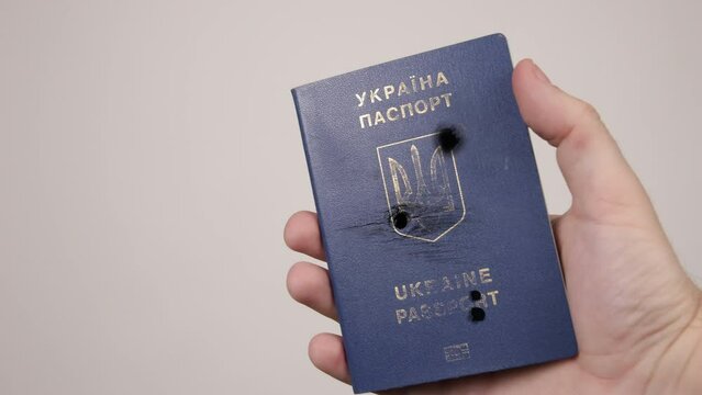 War between Russia and Ukraine. The concept of murder, occupation, aggression. Male hand holds a blue passport of Ukraine.