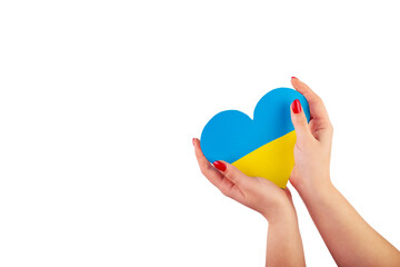 Fototapeta premium The hand of a young Ukrainian girl holds a heart of a yellow-blue flag on isolated white background. The concept of participation of the Ukrainian people in the war with Russia. Not war concept
