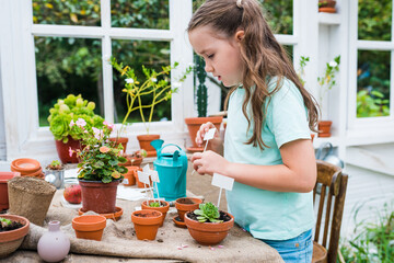 Activities for kids in the garden. Girl learning how to care for plants, growing and watering flowers in pots. Gardening for children concept