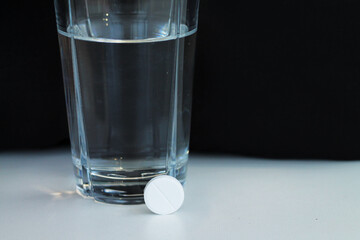 Glass of water and an effervescent tablet or pain killer pill