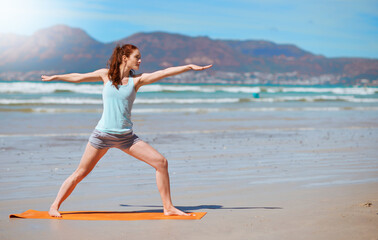 Be a warrior not a worrier. Shot of a young woman practicing her yoga routine at the beach.