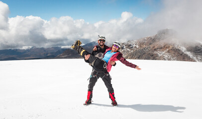 Couple enjoying snowy glacier summit together all geared up, obviously in love