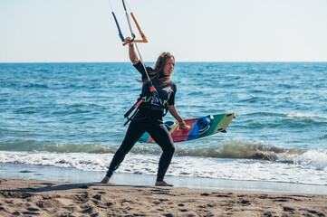 Woman holding kiteboard and going into the water