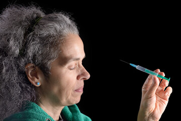 Woman pointing syringe to her face