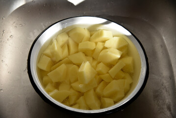 Peeled potatoes in strips in a white saucepan