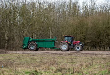 Fototapeta premium Case Puma 340 red tractor towing a Samson Flex-16 green muck spreader