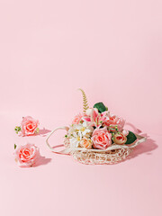 Floral arrangement with fresh flowers and crochet bag on pastel pink background. Creative Spring holiday bloom concept. Minimal festive romantic floral arrangement. Florist shop idea with copy space.