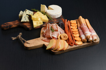 Appetizers table. Cheese, meat on dark background. Copy space