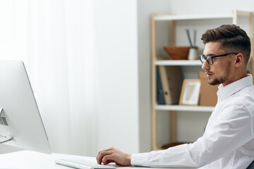 Obraz na płótnie Canvas handsome businessman in a white shirt sits at a computer work documentation executive