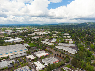 Fototapeta premium Shooting from a drone. Small town. Roofs of small one-story houses. Lots of greenery. Mountains are visible in the distance. Asphalt roads. There are many white clouds in the sky. Ecology, map.