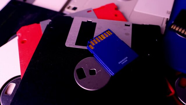 vintage retro electronic data storage devices from the 80s, 90s, cd disk, flash drives scattered on table. Stack of floppy disks, pendrive and hard disk in grey, black, blue, yellow, red, white