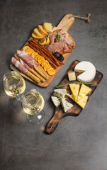 Two white wine glasses with buffet platter with cheese and meats, antipasti, prosciutto, charcuterie.