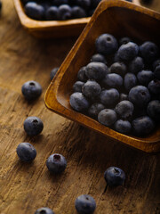 Close-up. Fresh blueberries in a bowl and on a wooden table. Vitamins, antioxidants, ingredient for pies, cakes, quick breakfast cereals. High angle view. There are no people in the photo.