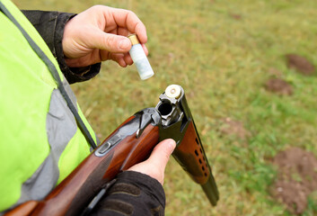 Shotgun in hunter hand. Hunter loads Cartridge (firearms) with shot into a double-barreled shotgun....