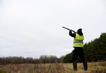 Hunter while hunting a wild bird. Hunters with gun and rifle on hunting in the fall season. Hunters during hunting in forest. The hunter shoots the birds in the sky.